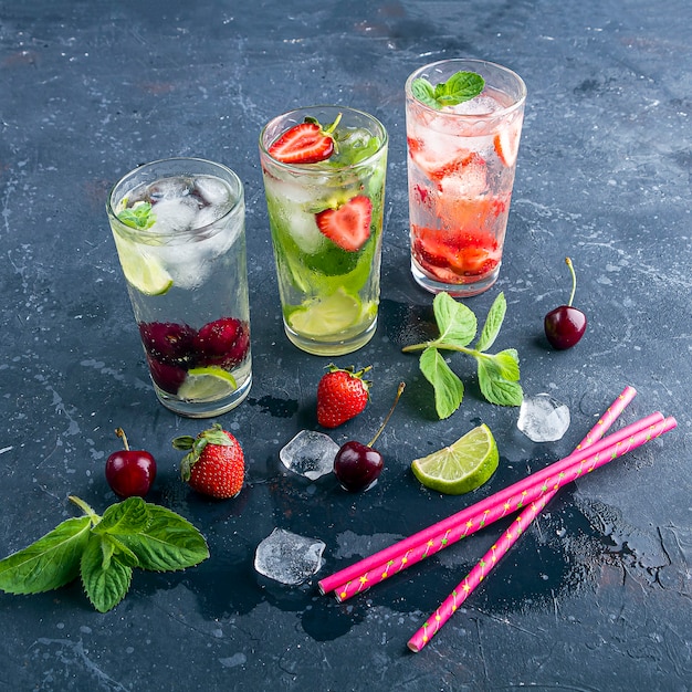 Zdjęcie pić z truskawką limonkowo wiśnią i miętą na ciemnym tle. koktajle mojito