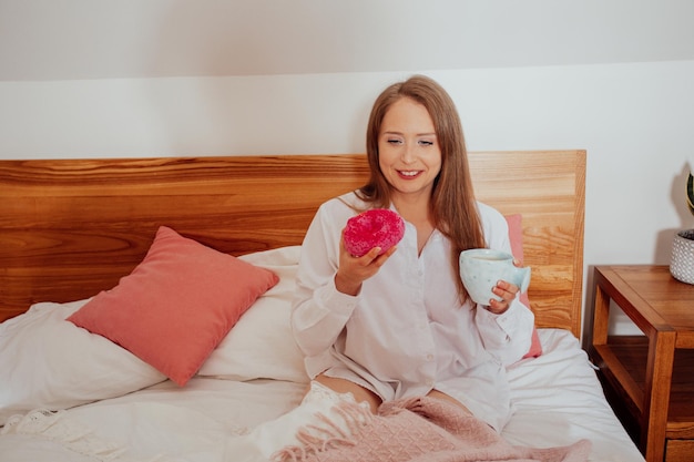 Picie kawy i jedzenie pączka na śniadanie w łóżku