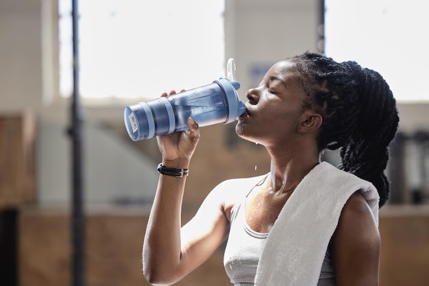 Picie wody i relaks po treningu fitness i treningu wysiłkowym atletki Kobieta z Nigerii pokryta potem, osiągając cel cardio sport na siłowni wellness i sportowej