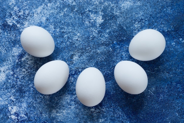 Pięć Białych Jaj Leży Na Podniesionym Niebieskim Tle W Kształcie Półkola.