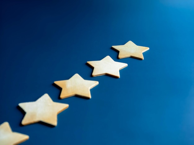Pięć drewnianych gwiazdek jako nagroda w rankingu doskonałości krok wykresu na niebieskim tle Ranking satysfakcji ocena klienta ocena jakości nagroda marketing koncepcje rozwoju biznesu i sukcesu