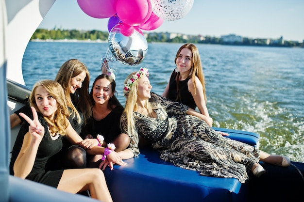 Zdjęcie pięć dziewczyn ubiera się na czarno, bawiąc się na jachcie przed jeziorem na wieczorze panieńskim