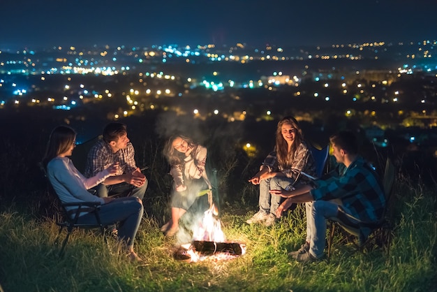 Pięć osób odpoczywa przy ognisku. pora nocna