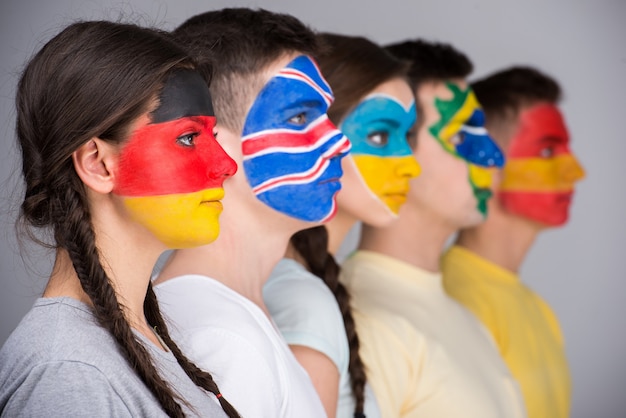 Pięć osób z flagami narodowymi namalowanymi na twarzach w profilu.
