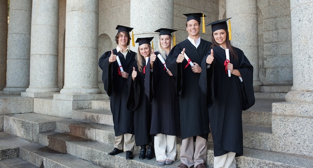 Pięć szczęśliwych absolwentów stwarzających kciuk