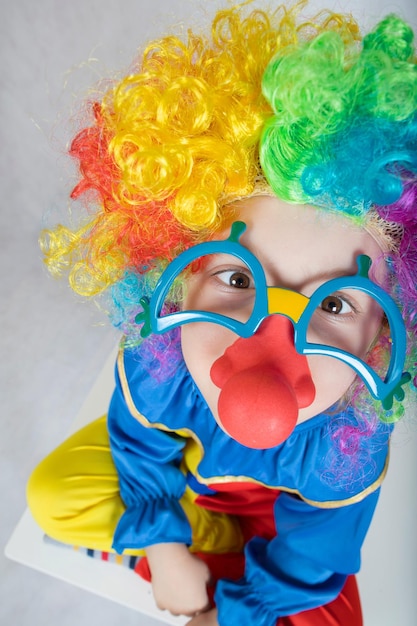 Pięcioletni chłopiec ubrany w kostium klauna i zabawne okulary z czerwonym nosem. Zbliżenie