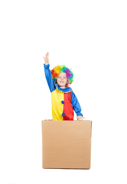 Pięcioletni chłopiec ubrany w kostium klauna próbuje wyskoczyć z kartonowego pudełka. Zbliżenie