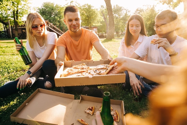 Pięciu Młodych Wesołych Ludzi Jedzących Pizzę I Pijących Piwo Na świeżym Powietrzu.