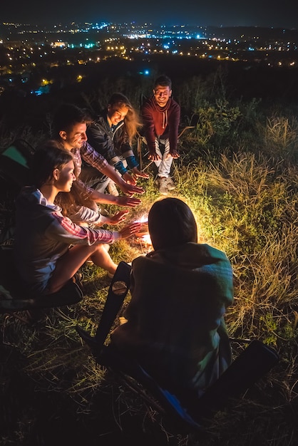 Pięciu przyjaciół grzeje się przy ognisku. wieczorna pora nocna