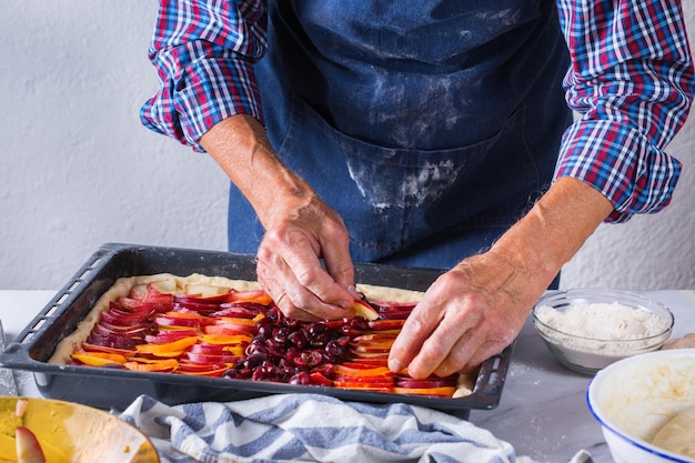 Pieczenie, jedzenie w domu, koncepcja zdrowej żywności i stylu życia, starszy piekarz, gotowanie, wyrabianie świeżego ciasta rękami toczenie z szpilką, rozprowadzanie nadzienia na torcie na kuchennym stole z mąką