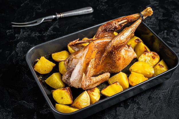 Pieczona Guineafowl perliczka z ziemniakami w naczyniu do pieczenia Czarne tło Widok z góry