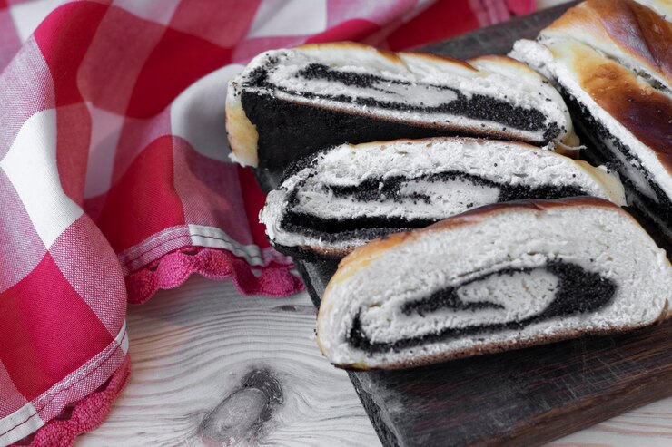 Zdjęcie pieczona rolka z nasionami maku trzy pocięte kawałki z bliska na drewnianym tle