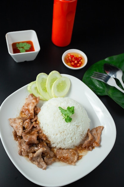 Pieczona wieprzowina z czosnkiem i pieprzem oraz pokrojonym ogórkiem podawana z ryżem jaśminowym białe danie popularne danie tajskie