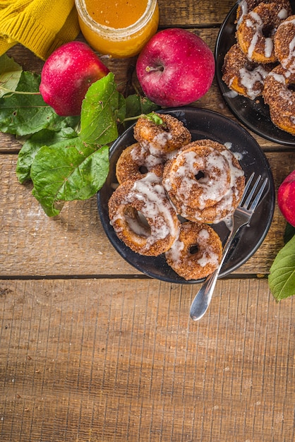 Pieczone pączki z cukrem, polewą cynamonową i polewą cukrową mżawką, na drewnianym tle ze świeżymi jabłkami