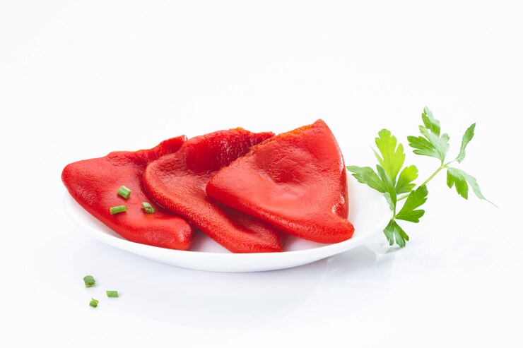 Pieczone papryki piquillo na białym talerzu z pietruszką na białym tle na powierzchni.