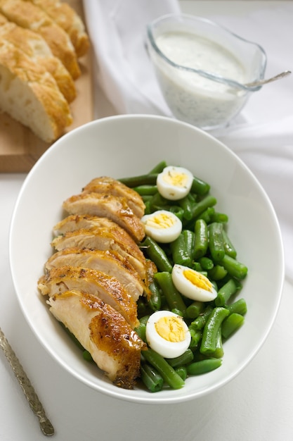 Pieczone piersi z kurczaka podawane z jajkiem sadzonym i gotowaną zieloną fasolką.