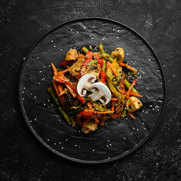 Pieczone warzywa z woka na czarnym kamiennym talerzu Kuchnia azjatycka Widok z góry