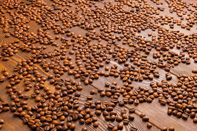 Zdjęcie pieczone ziarna kawy rozłożone na drewnianej desce z pełną klatką w tle
