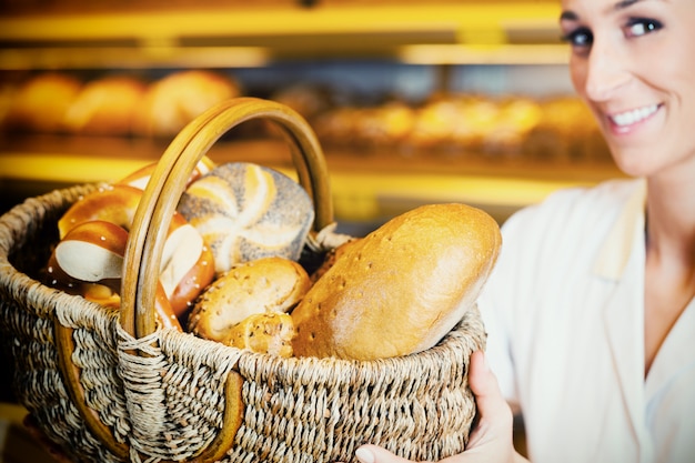 Piekarniana kobieta w backer sprzedaje chleb w koszu