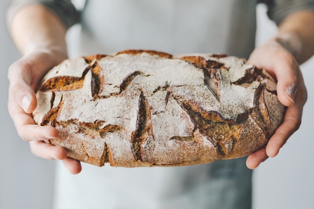 Zdjęcie piekarz lub szef kuchni trzyma świeży chleb