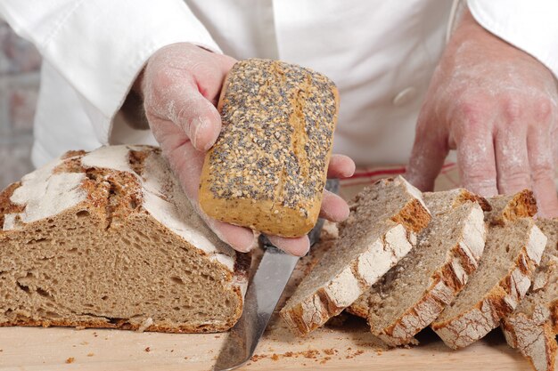 Piekarz ręce ze świeżego chleba na stół z drewna
