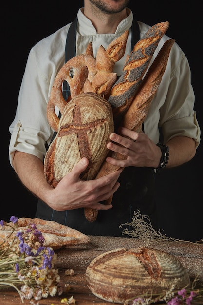 Piekarz trzyma świeży organiczny chleb i bagietkę