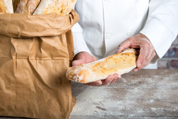 Piekarz trzyma tradycyjne chleb francuskie bagietki