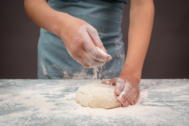 Piekarz ugniatający ciasto na pizzę lub chleb rzemieślniczy przygotowuje składniki do pieczenia ciasta