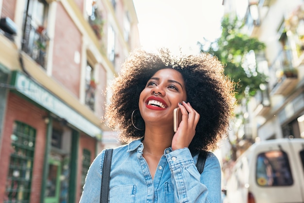 Piękna afro amerykańska kobieta za pomocą telefonu komórkowego na ulicy. Koncepcja komunikacji.