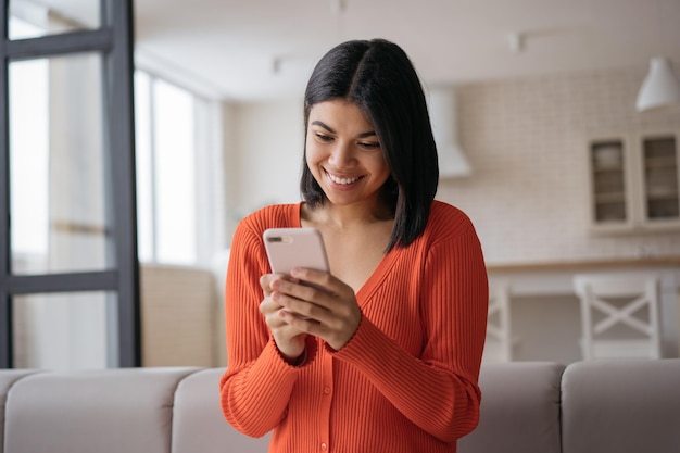 Piękna Afroamerykanka nosi SMS-y na smartfonie, pracując w domu