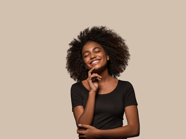 Piękna afrykańska kobieta czarna koszulka portret afro fryzura dotykająca jej twarzy Kolor tła brązowy