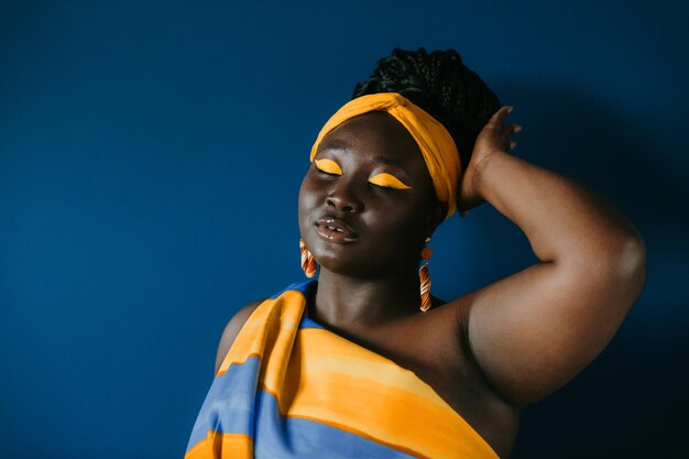 Zdjęcie piękna afrykańska kobieta w tradycyjnym afrykańskim stroju i biżuterii dotykająca włosów