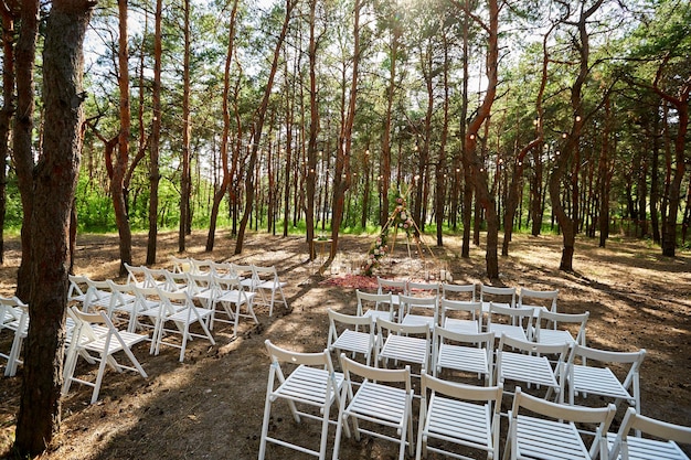 Piękna artystyczna dekoracja łuku tipi na plenerowej ceremonii ślubnej w sosnowym lesie z szyszkami