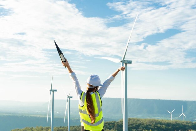 Piękna Azjatka Inżynier W Białym Hełmie Pracujący Z Dokumentem Na Farmie Energii Odnawialnej Kobieta Inspektor Kontrolująca Funkcjonowanie Turbin Wiatrowych Energia Zrównoważona Generator Energii Elektrycznej