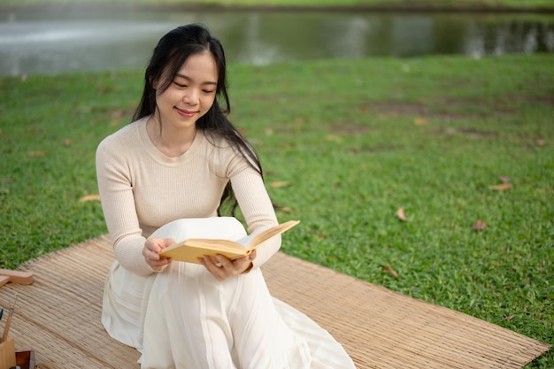 Piękna Azjatka lubi czytać książkę podczas pikniku w zielonym parku w weekend