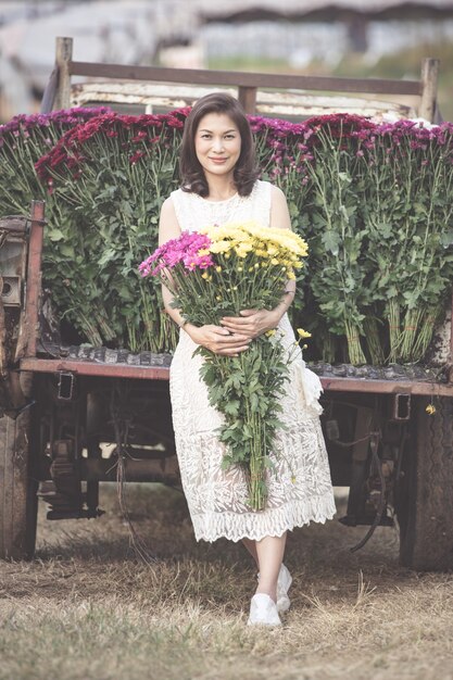 Piękna Azjatka trzymająca w rękach żółte kwiaty z dumą, właścicielka ogrodu kwiatowego zadowolona z dobrej jakości kwiatów na sprzedaż.