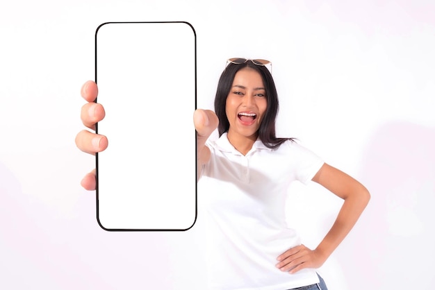Piękna Azjatycka brunetka Kobieta Ładna dziewczyna w białej koszuli Podekscytowany zaskoczony dziewczyna pokazując duży inteligentny telefon z pustego ekranu biały ekran na białym tle Wyświetl makiety obrazu