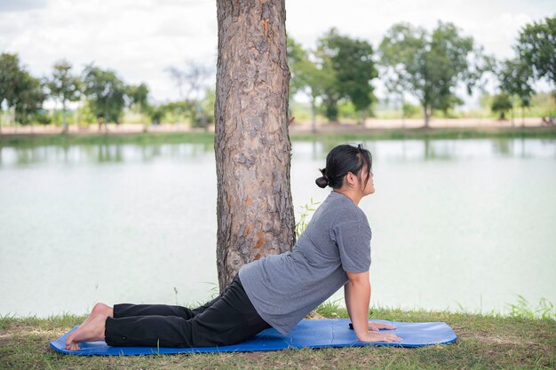 Piękna azjatycka gruba kobieta gra w jogę w parku Potrzebujesz szczupłego ciała?