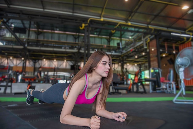 Piękna Azjatycka Kobieta Gra Fitness Na Siłownitajlandzka Dziewczyna Ma Szczupłe Ciałoczas Na ćwiczenialudzie Kochają Zdrowierozciąganie Ciała Przed Treningiemsportowa Kobieta Rozgrzewa Bodyplanking Na Podłodze