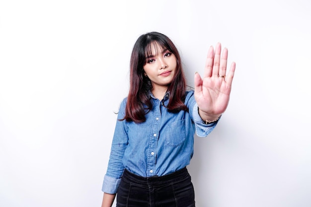 Piękna azjatycka kobieta ubrana w niebieską koszulę z gestem ręki stanowiącym stop lub zakaz z miejsca kopiowania