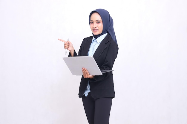 Piękna azjatycka kobieta z biura w hidżabie stoi wesoło w kamerach i gestuje w prawo i w lewo
