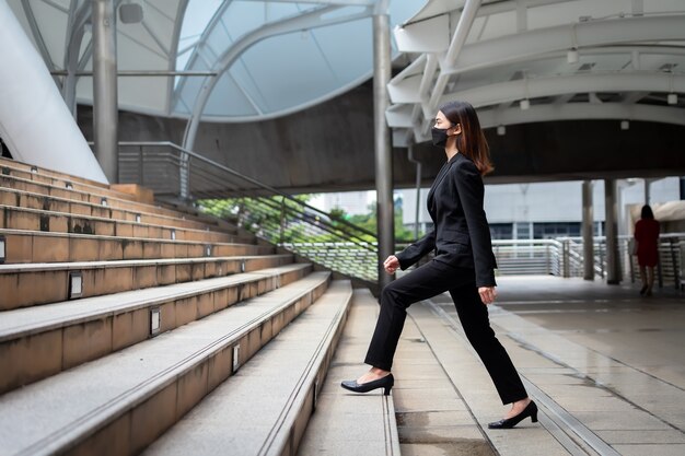 Zdjęcie piękna azjatycka tajska bizneswoman ubrana w czarny garnitur i chodząca po schodach do pracy w bangkoku w tajlandii.