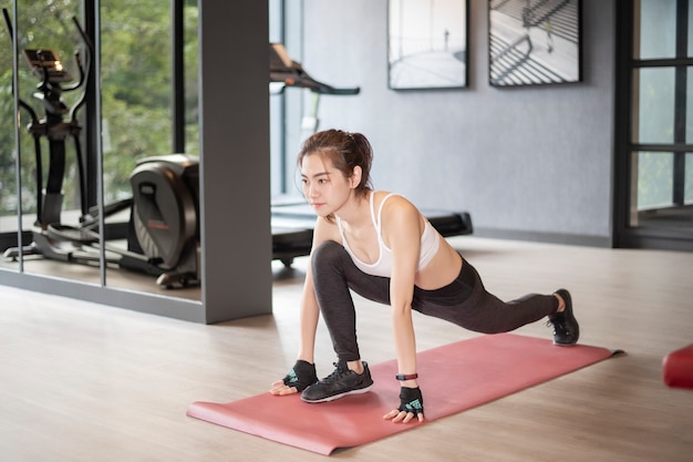 Piękna azjatykcia kobieta robi ćwiczeniu w gym