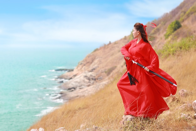 piękna azjatykcia kobieta w czerwonym chińskim kostiumu z czarnym mieczem