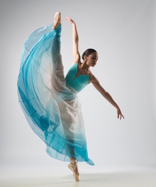 Piękna baletnica tańczy z niebieskimi i białymi ubraniami. Tańczyła na balerinkach.