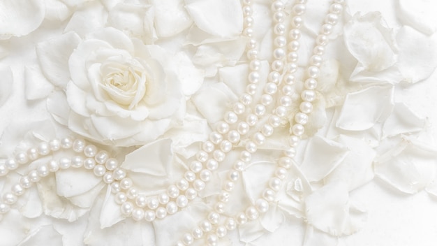 Piękna biała róża i naszyjnik z pereł na tle płatków. Idealny na kartki okolicznościowe na ślub, urodziny, Walentynki, Dzień Matki