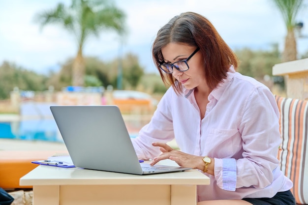 Piękna biznesowa kobieta po czterdziestce pracująca zdalnie na laptopie