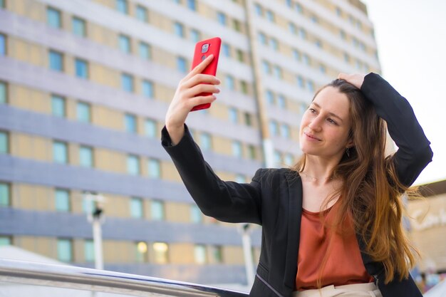 Zdjęcie piękna bizneswoman dorywczo robiąca selfie z telefonem komórkowym na zewnątrz