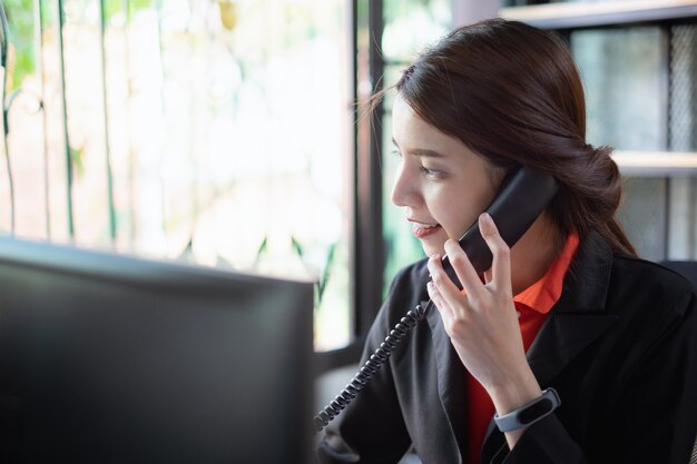 Piękna bizneswoman dyskutuje z partnerem telefonem w biurze.