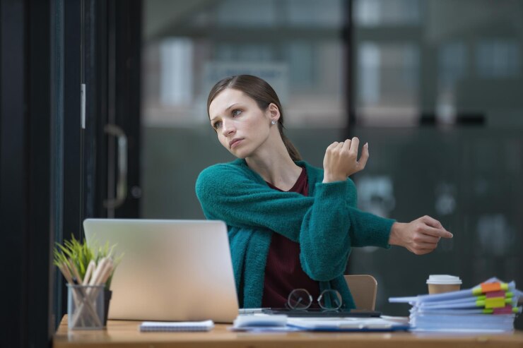 Piękna bizneswoman rozciągając ręce w biurze